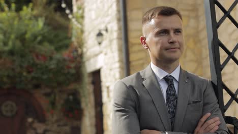 Groom-goes-down-the-alley-between-bushes-with-a-wedding-bouquet-to-his-beloved-bride