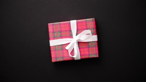 red gift box with white bow on black table  top view