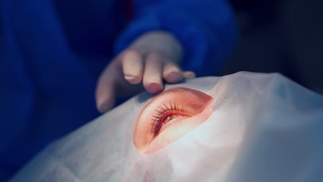 open eye of a patient during operation. close-up hands in gloves of a professional doctor treating patient's eye with special medical instruments.