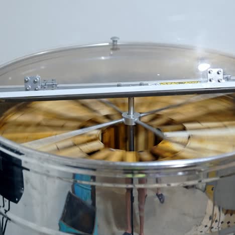 metal centrifugal machine pumping organic honey. honey extractor is spinning with frames to press out honey from honeycombs