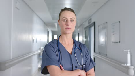 portrait of caucasian female doctor wearing scrubs and stethoscope in corridor, slow motion