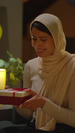 Vertical-Video-Of-Woman-Giving-Female-Friend-Birthday-Present-At-Home-With-Party-Balloons-In-Background-2