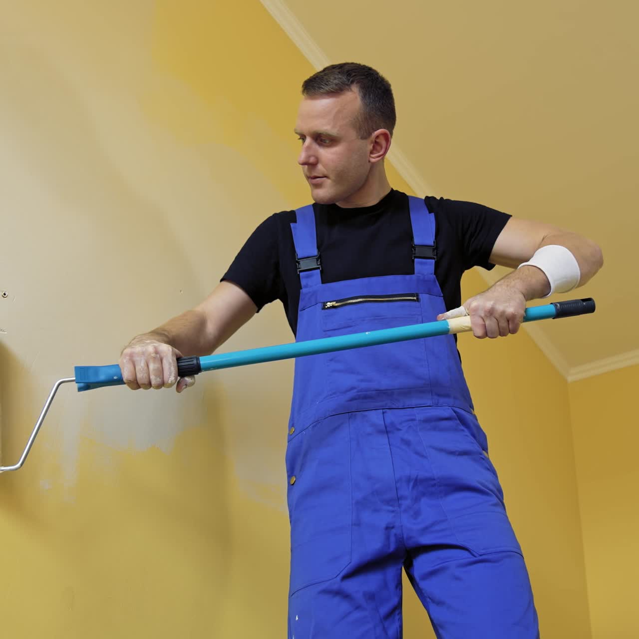 Man painting walls in apartment. Young man renovating new house and painting interior walls