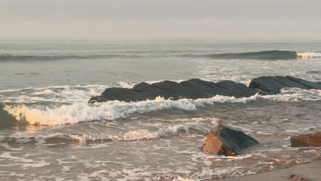 Sea-waves-splash-over-the-stony-and-rocky-coastline-of-the-Spanish-shores-during-the-evening,-illustrating-the-rugged-beauty-and-power-of-nature