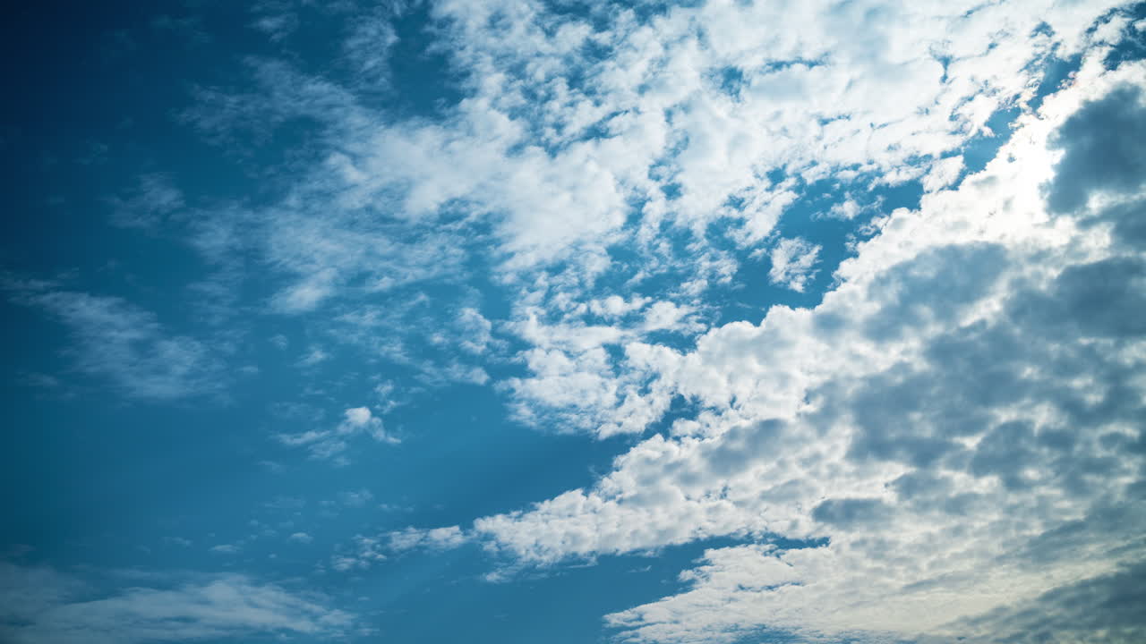 Blue sky with white clouds. Natural atmospheric phenomena of cloud formation. Summer timelapse of fluffy clouds. Sunlight