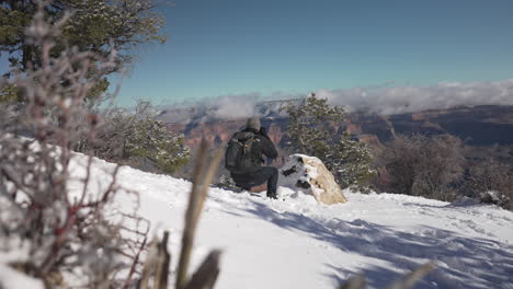 hombre agachado en la nieve tomando una foto del gran cañón - invierno, arizona, gran cañón, turista, fotógrafo