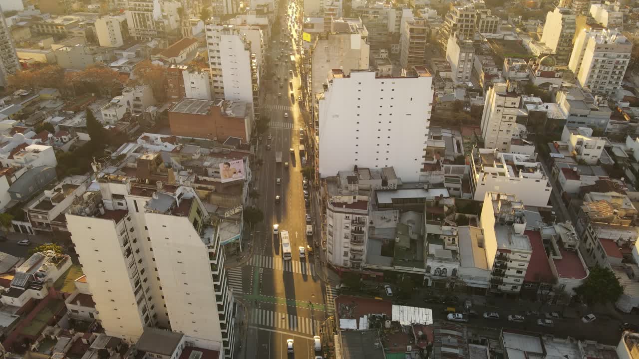 vuelo aéreo de drones sobre avenida frecuentada en buenos aires durante la puesta de sol dorada - toma de arriba hacia abajo del distrito central con edificios altos y rascacielos