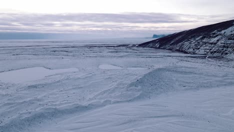 Aerial-panoramic-view-over-Skaftafellsjokull-glacier-surrounding-mountains,-in-Iceland,-covered-in-snow,-at-sunset