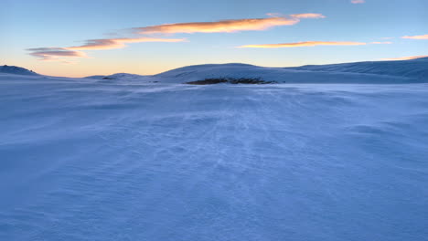 Blowing-snow-is-blown-away-by-the-wind-in-a-wintry-landscape-after-sunset