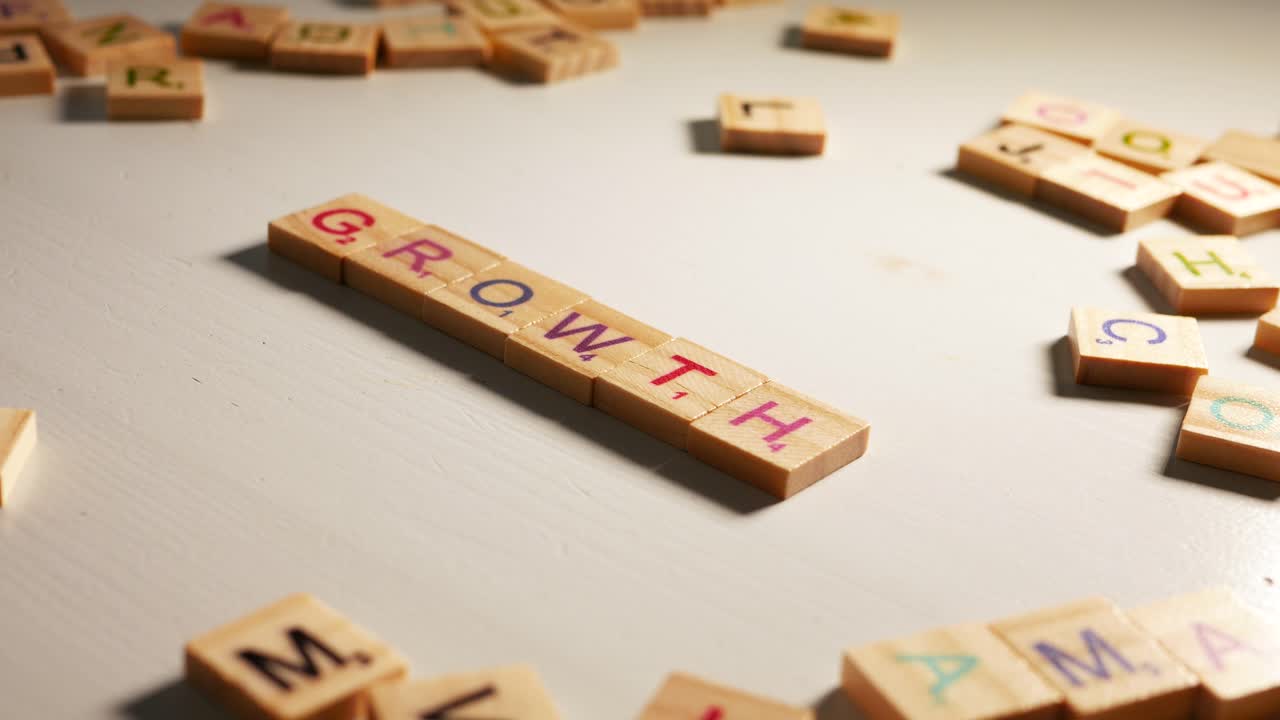 A person writing Growth with wooden tiles letters