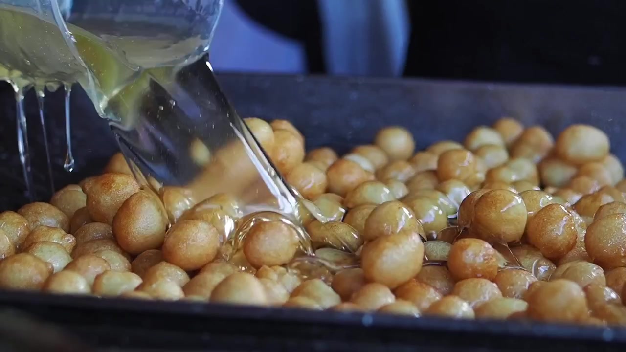 Chef che versa sciroppo su ciambelle Loukoumades appena fritte