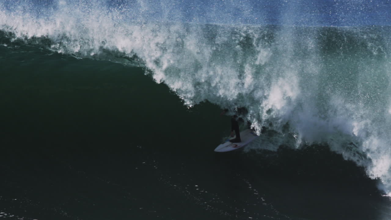 Shadowy curl forms dramatic barrel as surfer rides into narrowing hollow tube
