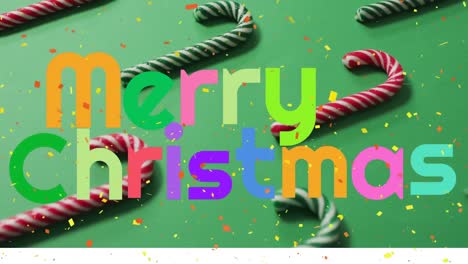 Colorful-merry-christmas-text-banner-against-confetti-falling-over-candy-canes-on-green-surface