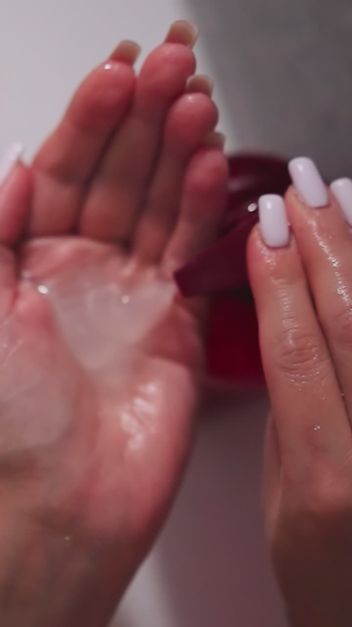 mujer bombea champú en la palma en la unidad de ducha de cerca. dama vierte jabón líquido del dispensador en el baño. mujer limpia el cuerpo con producto cosmético