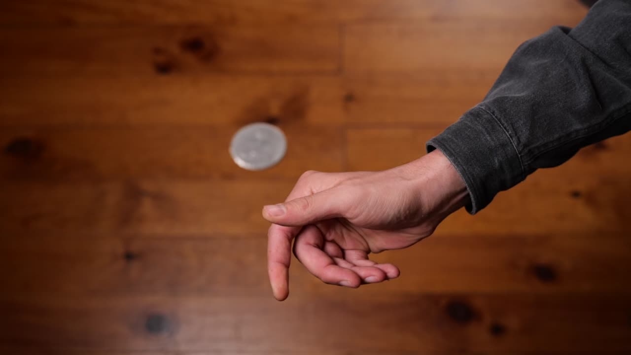 lanzar una moneda a mano para voltear cara o cruz y atraparla sobre la marcha