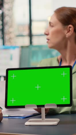 vertical video group of businesswomen reviews project analytics with green screen