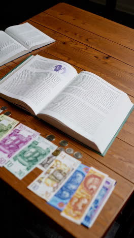 open book and georgian currency on a wooden table