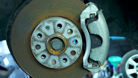 close up view of vehicle brakes, discs and pads in a mechanic workshop