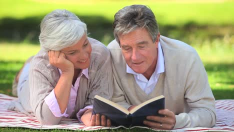 pareja madura leyendo un libro afuera