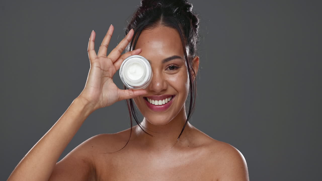 mujer feliz, cara y crema para el cuidado de la piel