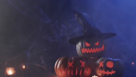 Video-of-halloween-carved-pumpkins-and-smoke-with-copy-space-on-blue-background