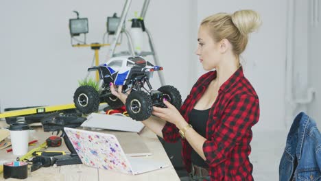 young woman inspecting radio controlled car at workbench