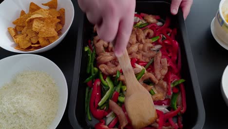 mezclar filete de pechuga de pollo con pimiento y tiras de cebolla en una bandeja para hornear