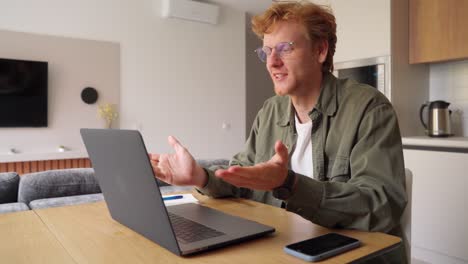 smiling ginger irish man having video call over laptop computer at home