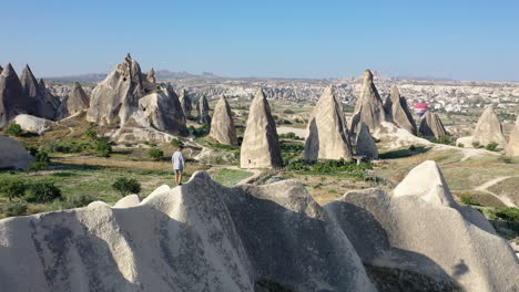 rotación reveladora cinemática drone tiro de un hombre escalando sobre la cima de una colina en capadocia, turquía