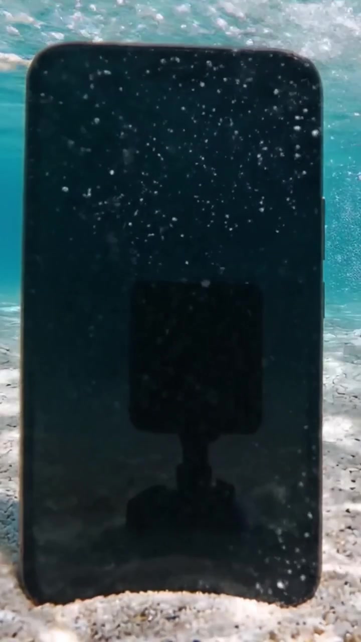 Un encuentro submarino: Explorando la fascinante escena de un teléfono móvil sumergido bajo aguas cristalinas y arena suave.