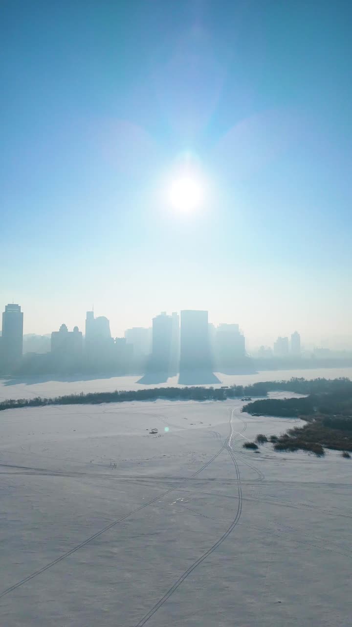 Vertical aerial view of Harbin’s winter skyline, featuring snow-covered landscapes, and the frozen Songhua River. China