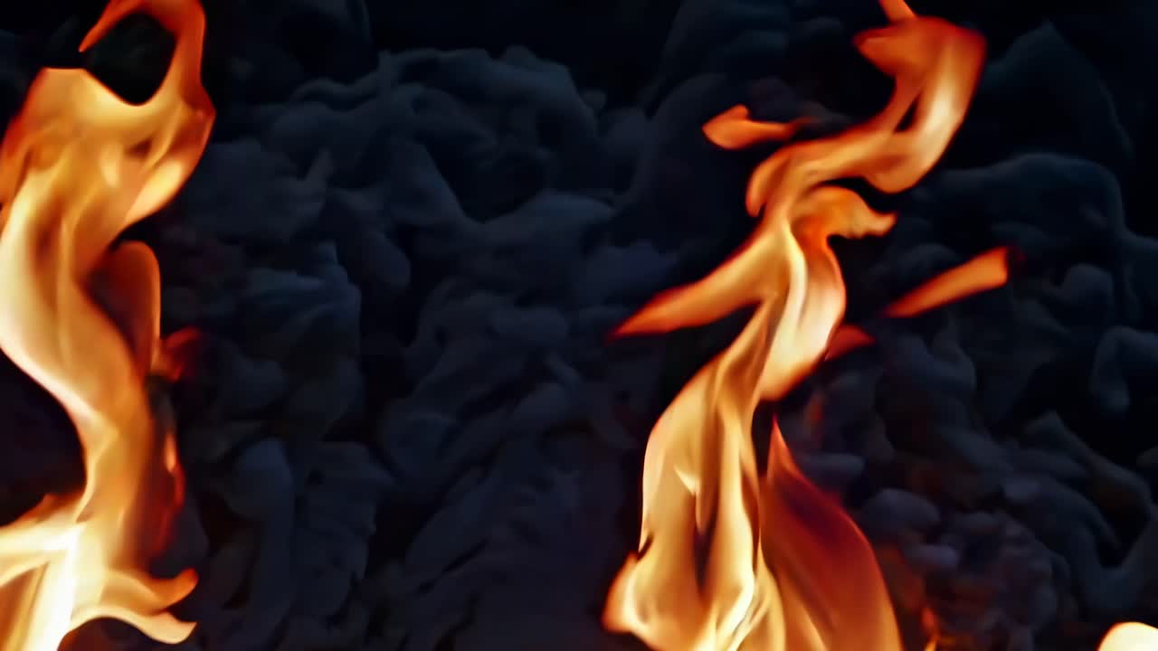 Video ravvicinato di vivaci fiamme che danzano su uno sfondo scuro, ripreso da un angolo basso