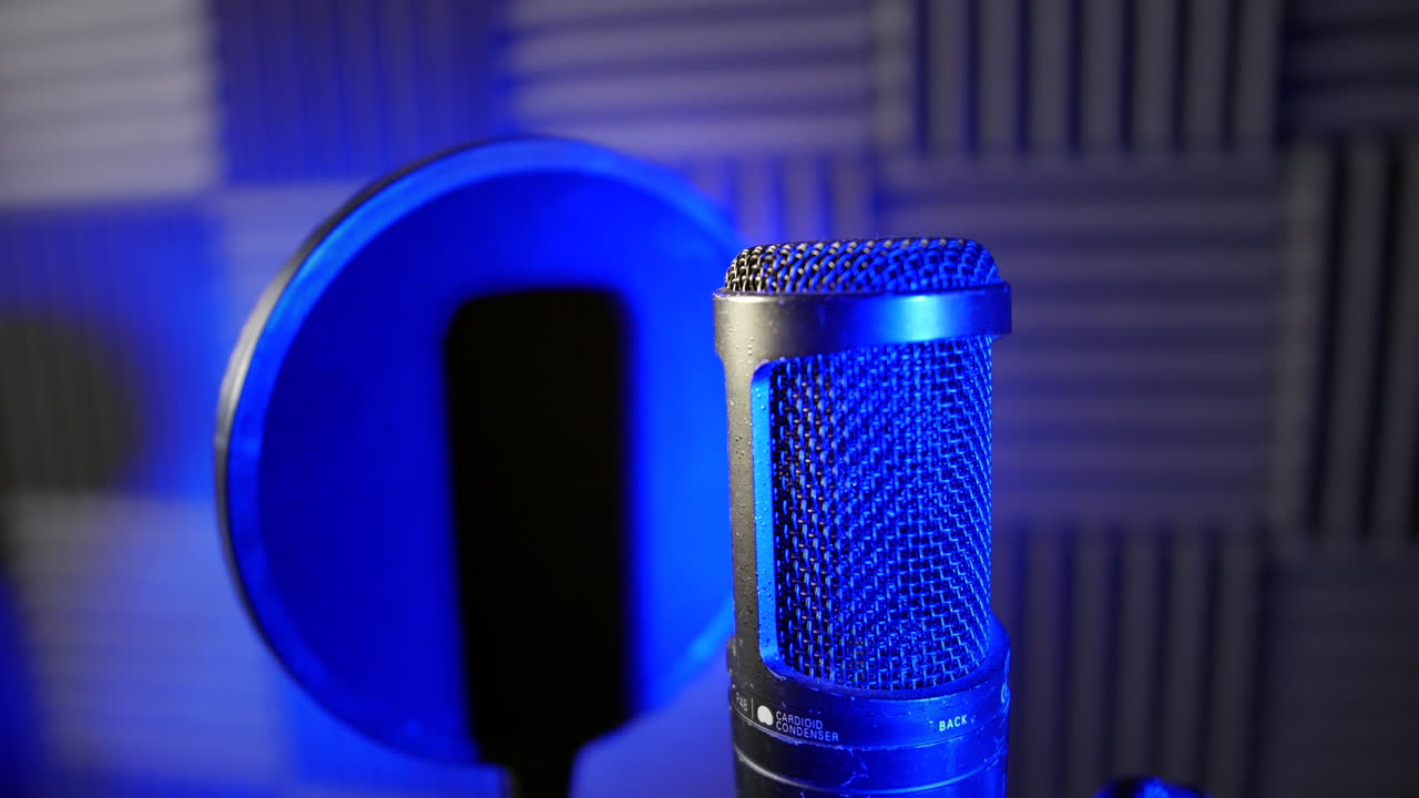 toma de seguimiento de un micrófono profesional y un escudo pop en una cabina vocal de estudio de grabación con espuma acústica detrás