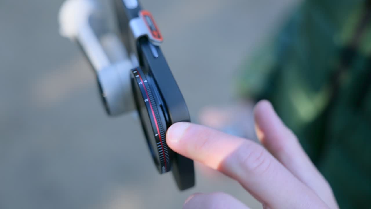 Adjusting Magnetic Lens Filter Attached To Smartphone Mounted On Gimbal Stabilizer. closeup shot