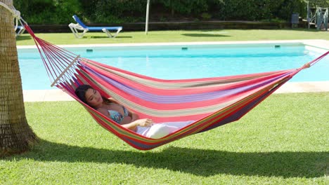 mujer en hamaca en un complejo tropical con piscina