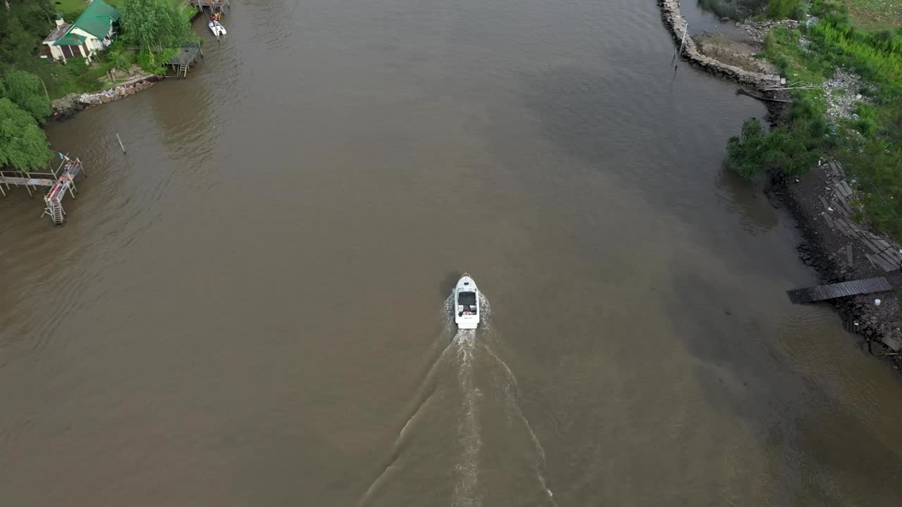 Drone che segue un singolo motoscafo che naviga su un corso d'acqua in un luogo tropicale.