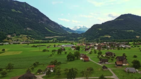 drone shot of a small village in the swiss alps surrounded by forest mountains, switzerland, europe