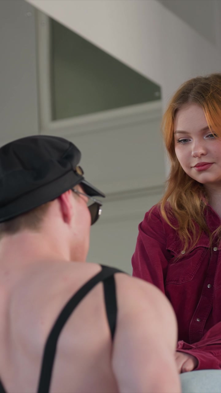 Close up of man and woman interacting indoors with white cloth. Man gestures while holding object young person observes attentively. Indoor setting features light colored walls