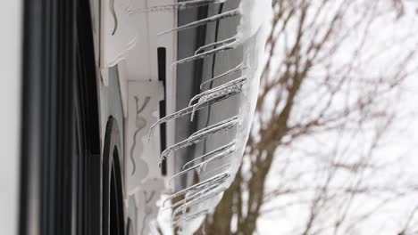 tilting shot of icicles melting off roof in 4k
