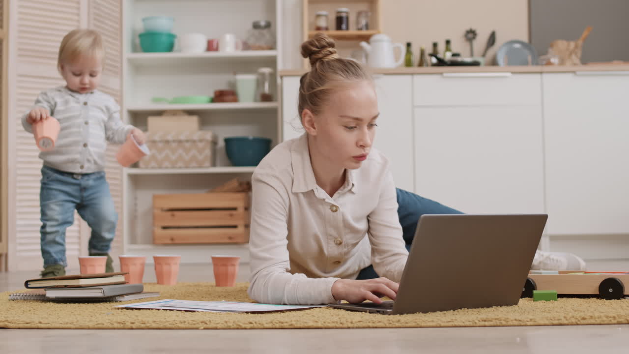 Woman Using Laptop while Toddler Playing