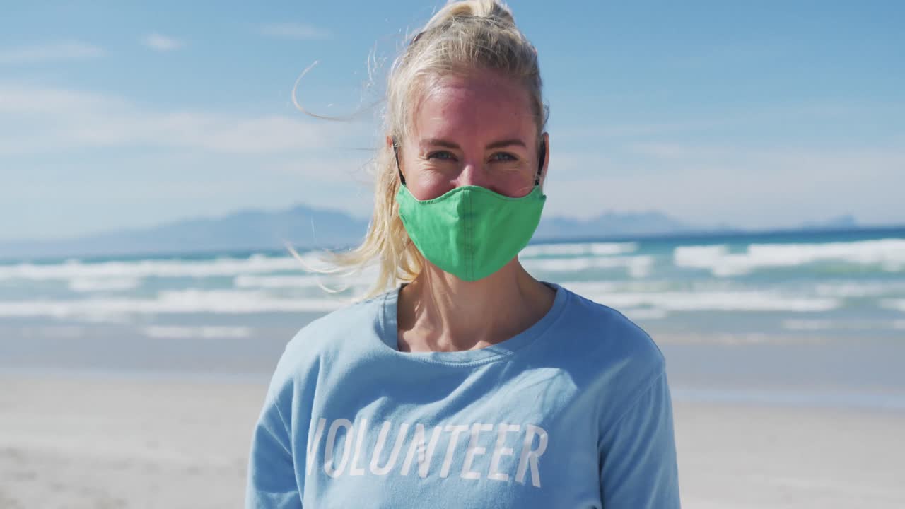 카메라 를 바라보는 자원 봉사자 티셔츠 와 얼굴 마스크 를 입은 백인 여성 의 초상화