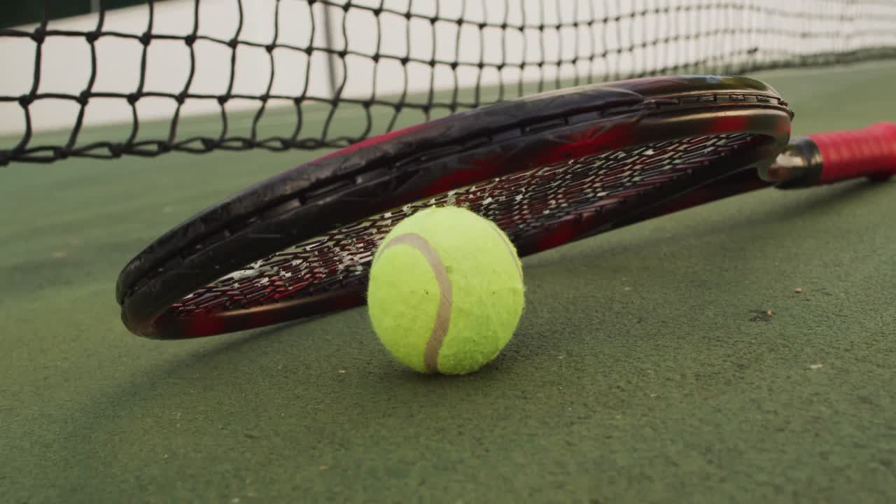 Video of tennis racket and ball lying on tennis court