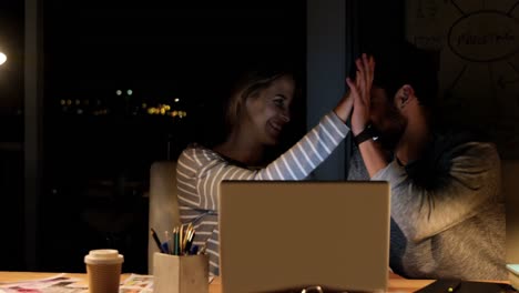 Colleagues-discussing-over-laptop-and-giving-high-five