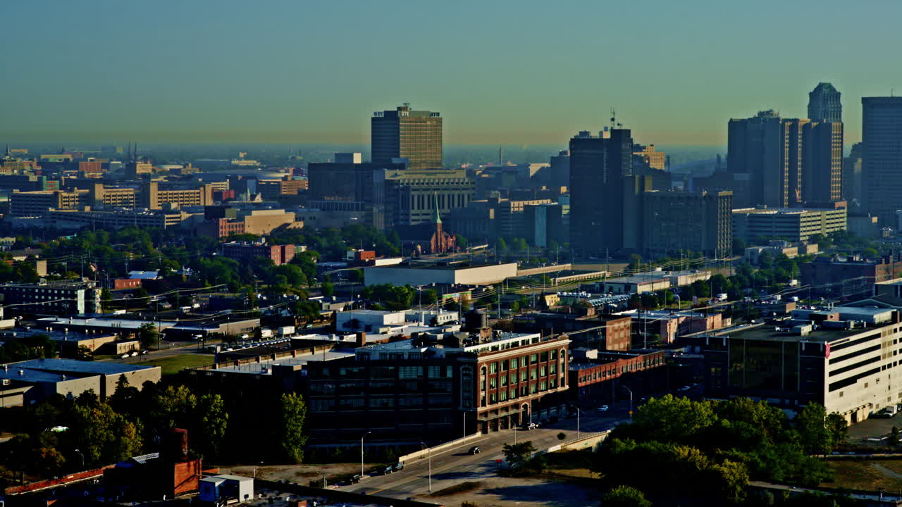 Drone shot sweeping across Detroit River toward skyline with freighter passing beneath