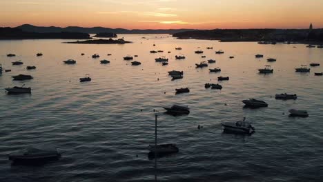 drone dolly shot of coast line with boats in the water with sunset in the background