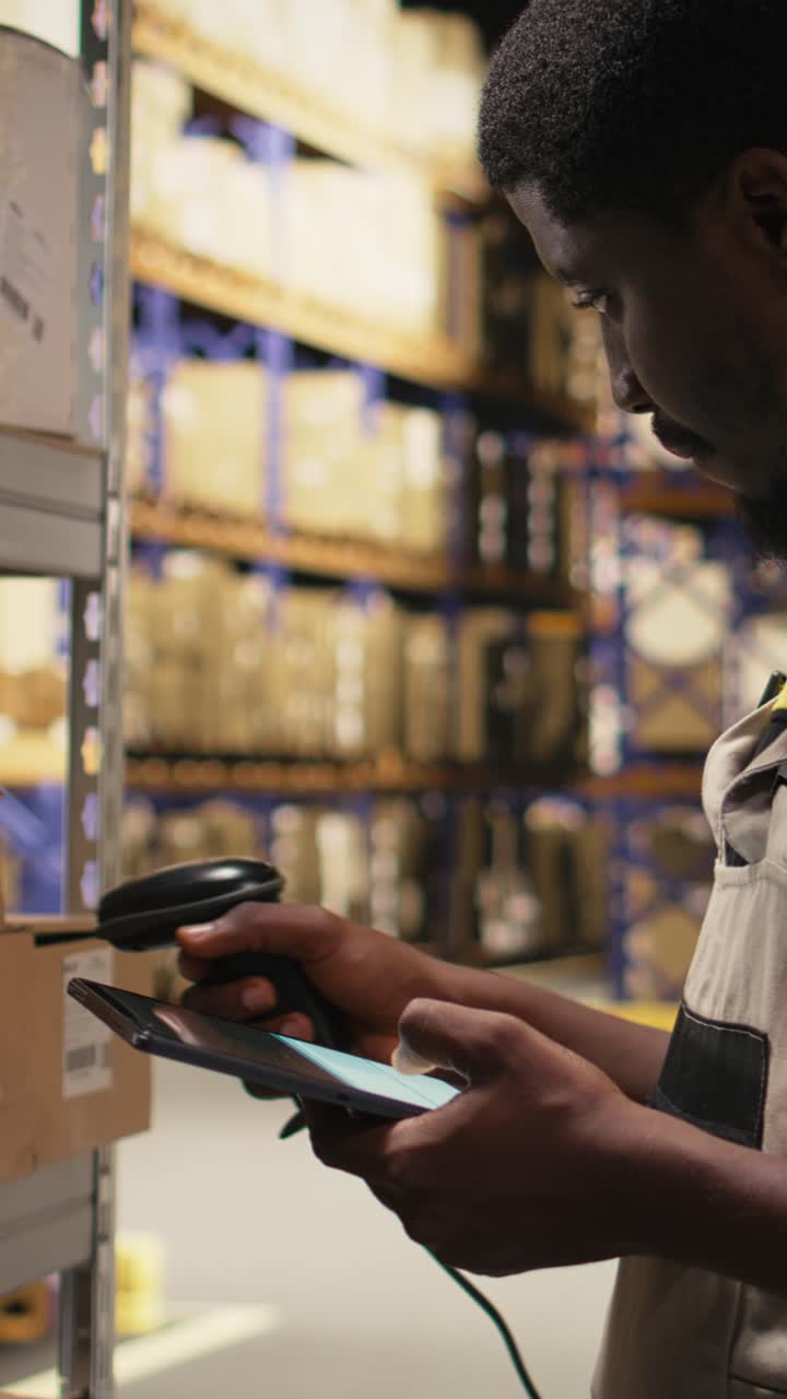 Vertical Video African American male employee scanning packages in a large warehouse