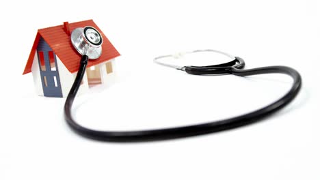 Close-up-of-house-model-and-stethoscope-against-white-background