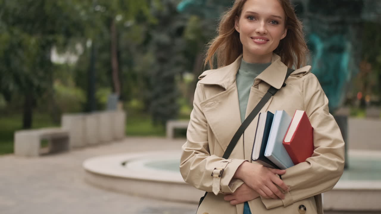 estudiante caucásica mirando a la cámara y sonriendo al aire libre.