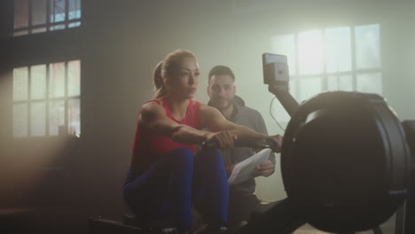woman working out on a rowing machine with a trainer