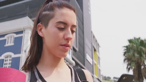mujer caucásica con su teléfono y colchoneta de yoga